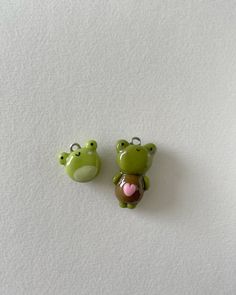 two green frog keychains sitting next to each other on a white table top