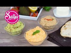 small bowls filled with hummus, bread and vegetables on top of a wooden table