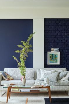 a living room filled with furniture and a blue brick wall behind the couch is a coffee table