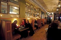 people sitting at tables in a restaurant with pictures on the wall