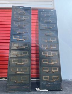 two tall metal filing cabinets sitting next to each other in front of a red garage door