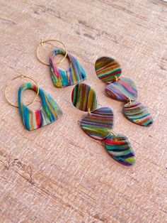 five different shaped earrings sitting on top of a wooden table