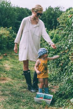 a woman and child are picking berries off the tree