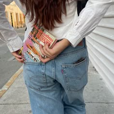 a woman standing on the sidewalk with her back turned to the camera and holding money in her pocket