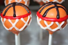 two orange cake pops with chocolate drizzle on them, sitting on top of each other