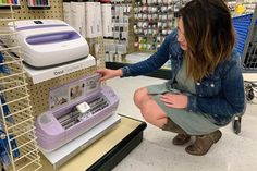 a woman kneeling down next to a machine in a store