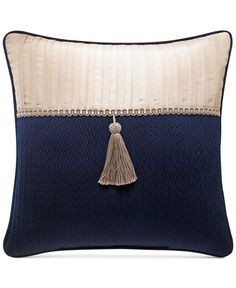 a blue and white pillow with a tasselled fringe on the front, along with a cream border