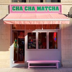 a pink bench sitting in front of a building with the name cha cha matcha on it