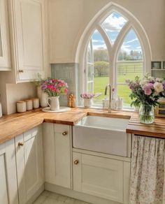 a kitchen with an arched window, sink and flowers in vases on the counter