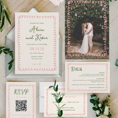 the wedding stationery is laid out with flowers and greenery