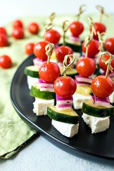 small appetizers with tomatoes, cucumbers and cheese on a black plate