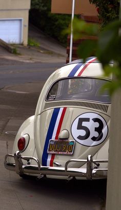 an old vw bug driving down the street with number 53 on it's side