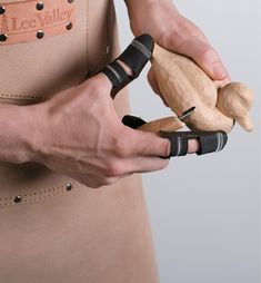 a person holding a wooden object in one hand and two other hands on the other