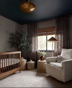 a baby's room with a crib, rocking chair and large potted plant