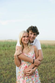 a man and woman hugging each other in an open field