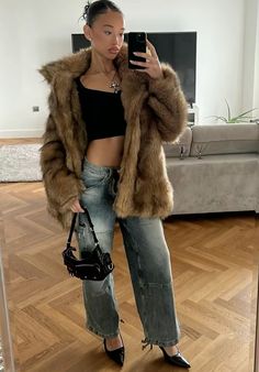 a woman taking a selfie with her cell phone in front of the camera wearing high heels and a fur coat