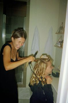 a woman blow drying her daughter's hair in the bathroom