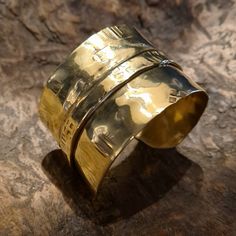 This unique and cool fold-formed brass wide cuff bracelet will always be the center of attention. Many of our designs are inspired by our fascination with the ancient cultures of the world, and this particular bracelet was inspired by the culture and lifestyle of the Vikings! This brutalist unisex cuff bracelet is made of brass. It is hammered, fold-formed, textured and polished entirely by hand in our studio. This handmade cuff bracelet is perfect for both women and courageous men... Its width is 4 cm. This cuff is adjustable, it can easily be squeezed for a tight fit or pried open for a looser fit. But even so, for its length, please select your size (considering the size of your wrist circumference) via the drop-down menu so that we can precisely prepare it for you.  Every piece in our Luxury Bronze Brass Bracelets, Luxury Bronze Cuff Bracelet As Gift, Unique Gold Wide Band Cuff Bracelet, Unique Gold Wide Band Bracelet, Gold Brass Wide Band Cuff Bracelet, Gold Brass Cuff Bracelet With Wide Band, Handmade Gold Cuff Bracelet With Wide Band, Handmade Wide Band Gold Cuff Bracelet, Gold Handmade Wide Band Cuff Bracelet