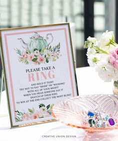 there is a sign that says please take a ring on the table next to some flowers