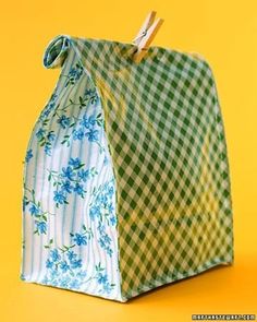 a green and white checkered paper bag with blue flowers on it, hanging from clothes pins