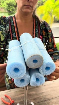 a woman is holding several blue items on a stick and some scissors are in front of her