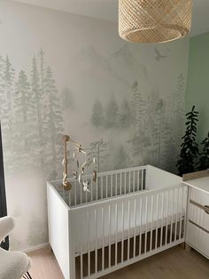 a baby's room with a crib, dresser and wallpapered trees