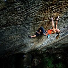 a man is climbing up the side of a rock face with his hands in the air