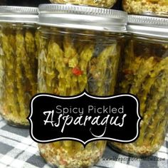 jars filled with pickled asparagus sitting on a checkered cloth covered table