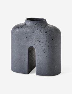 a gray vase with a small hole in the middle on a white background, it appears to be made out of concrete