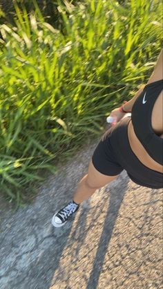 a woman in black shirt and shorts standing next to grass