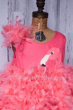 a pink flamingo dress on a mannequin with feathers around the neck and bottom