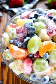 a glass bowl filled with fruit salad on top of a wooden table