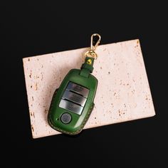 a green cell phone keychain sitting on top of a marble block