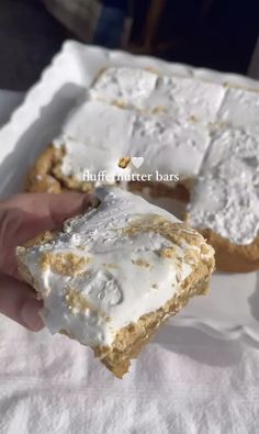 a person holding up a piece of cake with white frosting and gold sprinkles