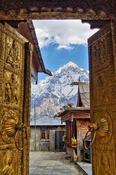 an open door leading to a small building with mountains in the backgrouds