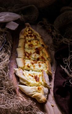 a long piece of pizza sitting on top of a wooden cutting board