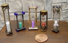 three hourglasses with different colored sand inside them on a table next to a penny