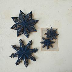 three blue paper snowflakes sitting next to each other on a white table top