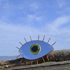 an eyeball shaped object sitting on top of a wooden fence