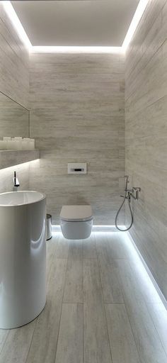 a bathroom with a toilet, sink and shower in the center is illuminated by recessed lighting