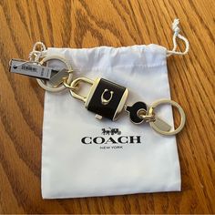 a coach keychain on a wooden table with a white bag in the background