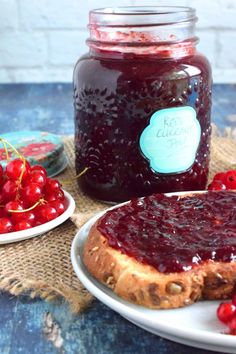 a jar of jam next to a plate with bread and cherries