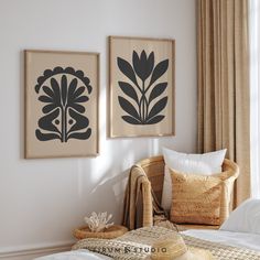 two black and white paintings on the wall above a bed in a room with wicker furniture