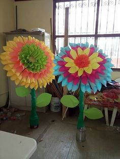 three colorful paper flowers are in the middle of a room with other items on the floor