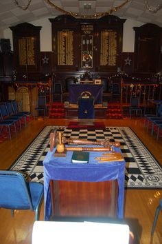 an empty room with blue chairs and a checkered table cloth on the floor in front of it