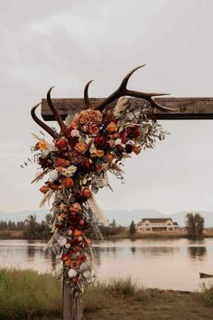 an antler's head is adorned with flowers and leaves on the side of a wooden pole