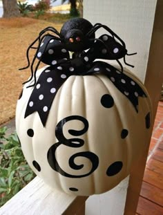 a white pumpkin decorated with black polka dots and a spider sitting on top of it