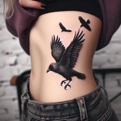 a woman's stomach with a black bird tattoo on her lower back and side