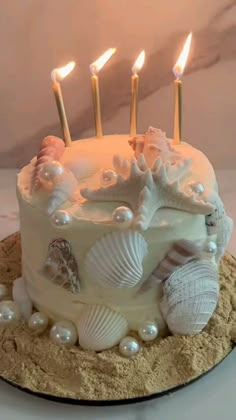 a white cake with seashells and candles on it