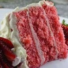 a piece of red velvet cake with white frosting and strawberries on the side